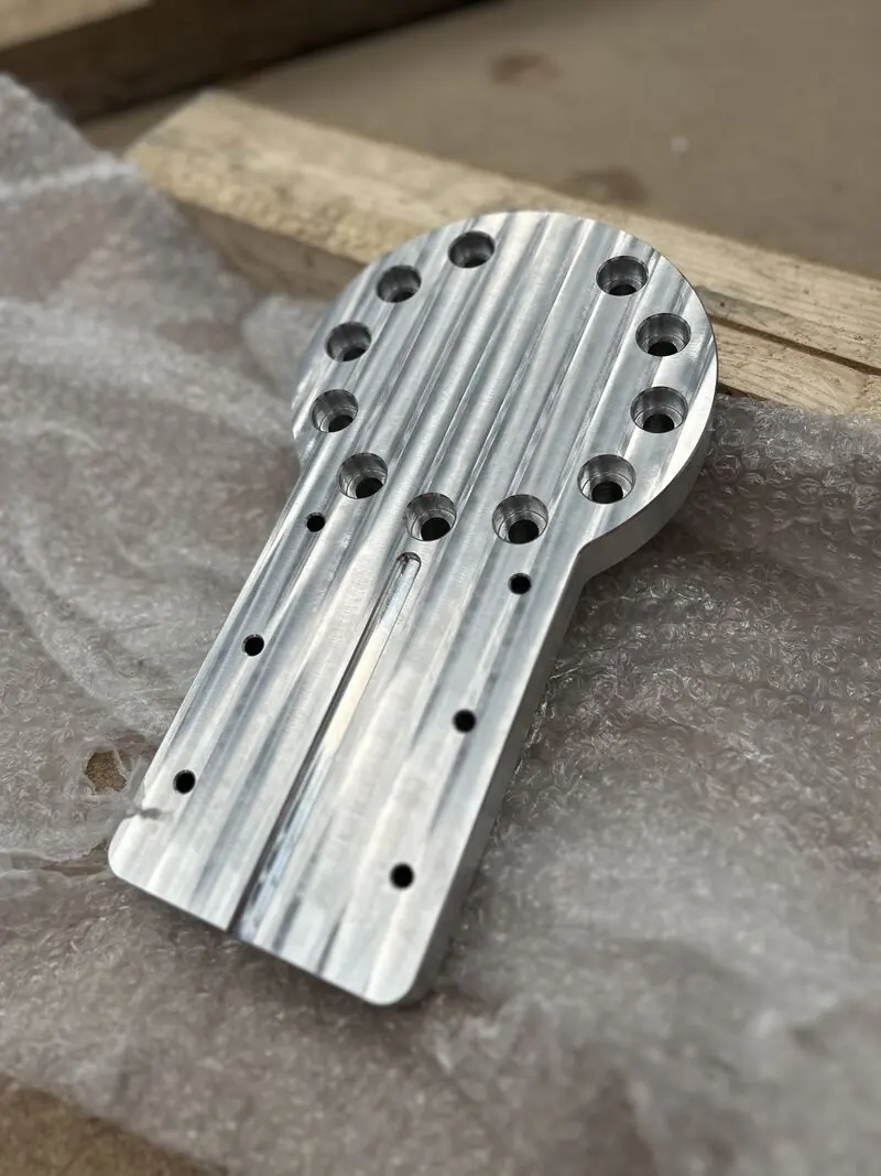 Machined aluminium spindle plate with a circular boss and bolt-hole pattern.